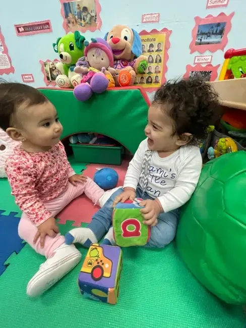 Two babies playing in the infant room